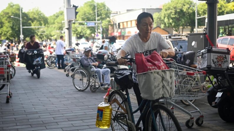 Un hombre en bicicleta con un barril de aceite de cocina sale de un supermercado en Pekín el 12 de junio de 2024. (Wang Zhao/AFP vía Getty Images)