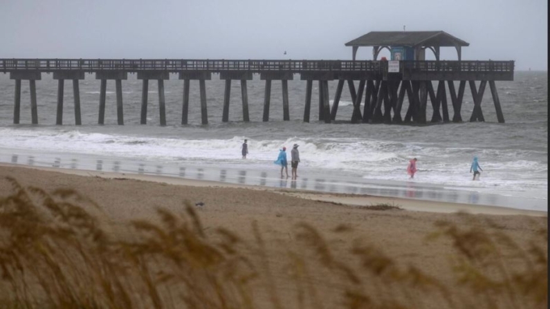 Los bañistas caminan cerca del muelle de Tybee mientras el viento y la lluvia de la tormenta tropical Debby comienzan a llegar a tierra en Tybee Island, Georgia, el 5 de agosto de 2024. (Stephen B. Morton/Foto AP)