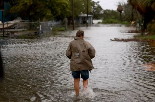 Una persona camina por una calle inundada por la lluvia y la marejada ciclónica del huracán Debby en Cedar Key, Florida, el 5 de agosto de 2024. (Joe Raedle/Getty Images)