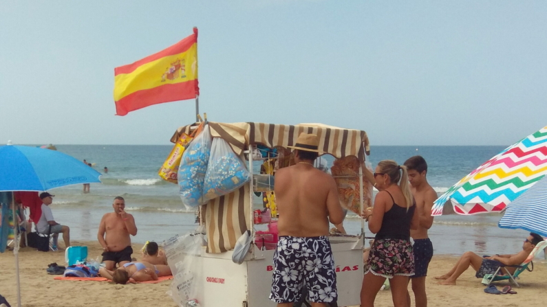 Un vendedor ambulante ofrece a los bañistas bebida fría o fruta fresca en la playa de Costa Ballena en Rota. EFE/Paloma Puente