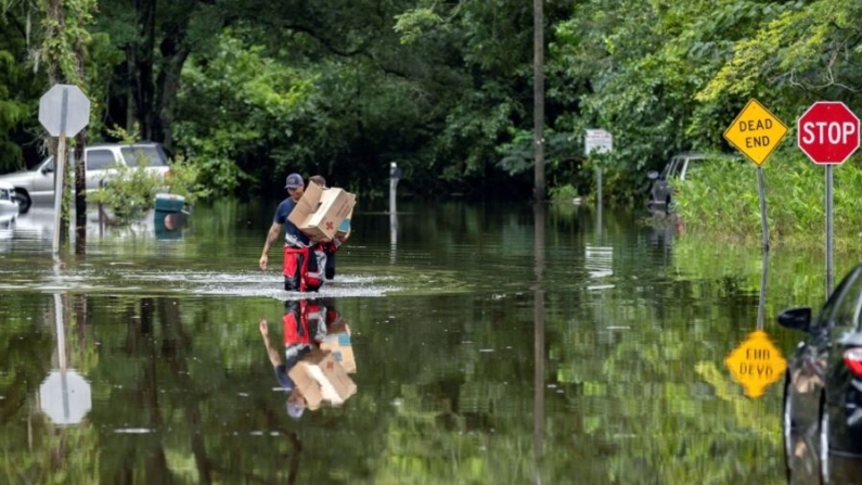 Los bomberos de Savannah Andrew Stevenson, por delante, y Ron Strauss llevan comida a los residentes del barrio de Tremont Park que quedaron varados por las inundaciones de la tormenta tropical Debby, en Savannah, Georgia, el 6 de agosto de 2024. (Stephen B. Morton/Foto AP)