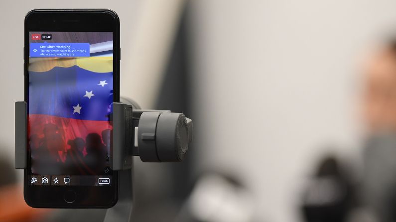 Imágenes de archivo: Frente: Celular muestra transmisión en vivo. (Kai Schwoerer/Getty Images) Fondo: Manifestantes venezolanos detrás de bandera. (JUAN BARRETO/AFP vía Getty Images) 