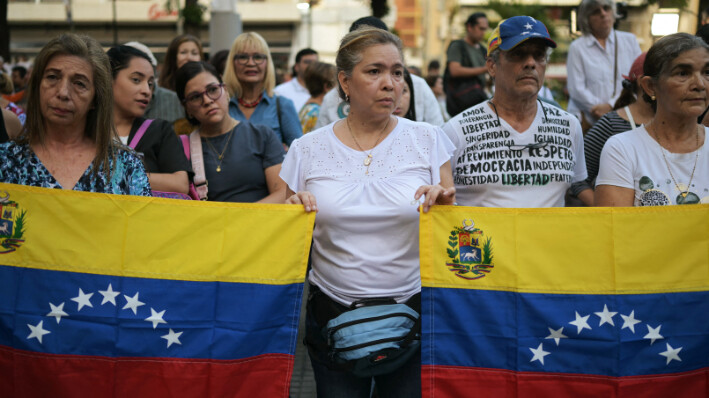 Personas sostienen banderas venezolanas durante una vigilia convocada por la oposición exigiendo la libertad de los presos políticos detenidos durante la protesta tras la impugnada reelección del presidente venezolano Nicolás Maduro en Caracas, 8 de agosto de 2024. (YURI CORTEZ/AFP via Getty Images)