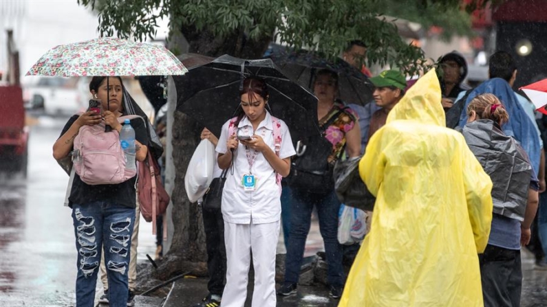 Ciudadanos caminan con paraguas e impermeables bajo una lluvia en la ciudad de Monterrey (México). Fotografía de archivo. EFE/ Miguel Sierra
