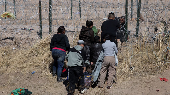 Migrantes intentan cortar una valla de alambre de púas instalada para evitar la entrada de migrantes ilegales a través del Río Bravo/Grande desde Ciudad Juárez, estado de Chihuahua, México, el 12 de febrero de 2024. (Herika Martinez/AFP vía Getty Images)
