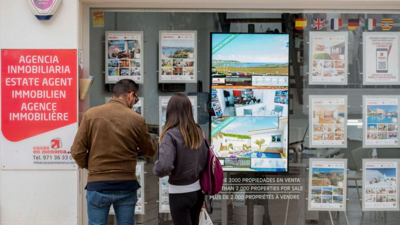 Imagen de archivo de una pareja observando las propiedades en venta anunciadas en el escaparate de una agencia inmobiliaria. EFE/ David Arquimbau Sintes