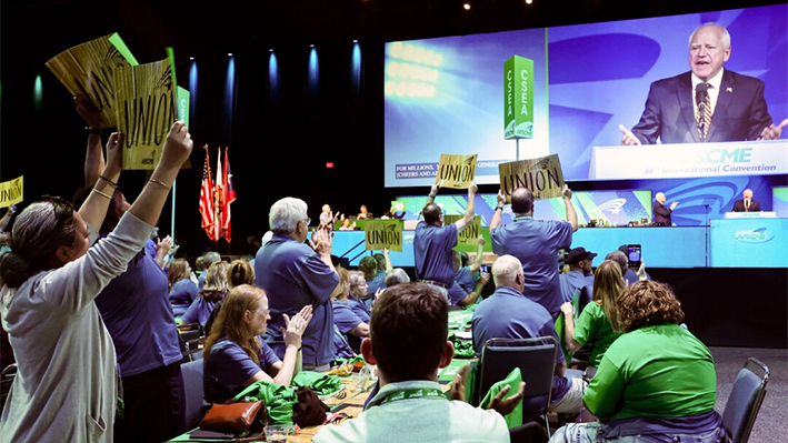 Los asistentes sostienen pancartas mientras el candidato demócrata a la vicepresidencia, el gobernador de Minnesota Tim Walz, habla en la 46ª Convención Internacional de la Federación Americana de Empleados Estatales, Municipales y de Condados (AFSCME) en el Centro de Convenciones de Los Ángeles, el 13 de agosto de 2024. (Mario Tama/Getty Images)