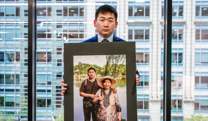 Simon Zhang, un arquitecto de la ciudad de Nueva York, sostiene una foto de él y su madre, que fue torturada hasta la muerte en China, en una mesa redonda que marca el 25º aniversario de la persecución del Partido Comunista Chino a Falun Gong, en Washington, el 17 de julio de 2024. (Caroline Li/The Epoch Times)