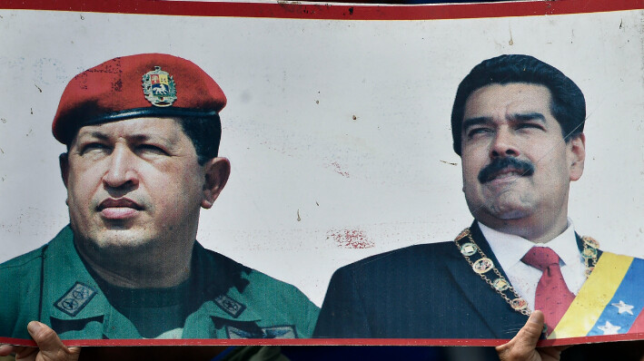 Un partidario del gobierno del presidente Nicolás Maduro sostiene una pancarta con los retratos del fallecido presidente venezolano Hugo Chávez (I) y el presidente Nicolás Maduro, mientras participa en una marcha en Caracas el 23 de enero de 2019. (LUIS ROBAYO/AFP vía Getty Images)