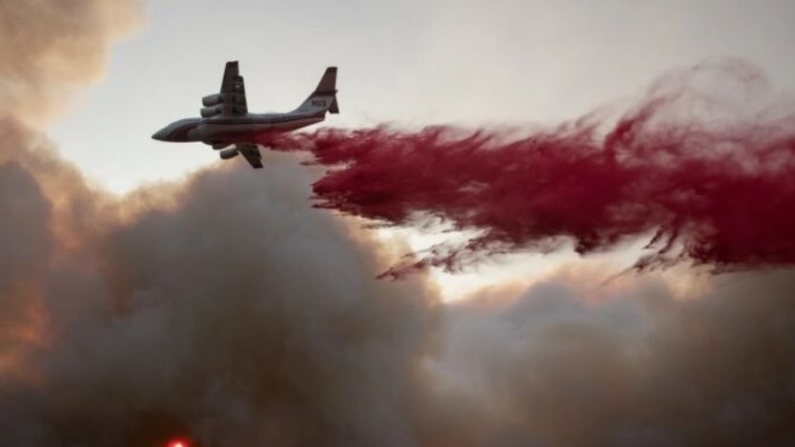 El sol se ve a través de una nube de humo mientras un avión deja caer retardante de fuego rojo en el Glass Fire en Deer Park, California, el 27 de septiembre de 2020. (Adrees Latif/Reuters)