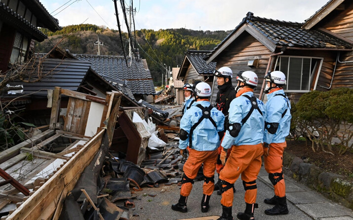 Bomberos inspeccionan  casas de madera derrumbadas en Wajima, prefectura de Ishikawa, el 2 de enero de 2024, un día después de que un gran terremoto de magnitud 7.5 sacudiera la región de Noto en la prefectura de Ishikawa. (Kazuhiro Nogi/AFP vía Getty Images)