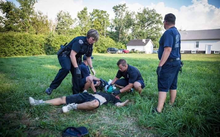 La policía local y los paramédicos ayudan a un hombre que sufre una sobredosis en el vecindario Drexel de Dayton, Ohio, el 3 de agosto de 2017. (The Epoch Times)