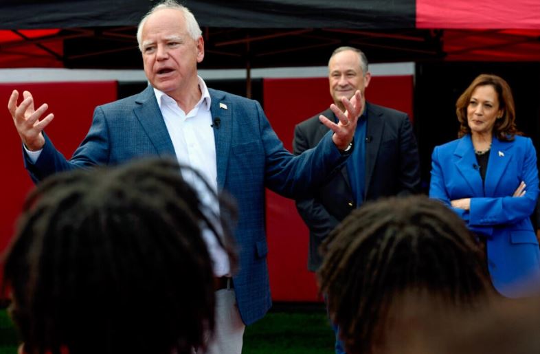 El candidato demócrata a la vicepresidencia, el gobernador de Minnesota Tim Walz, habla mientras la candidata demócrata a la vicepresidencia Kamala Harris, a la derecha, y su esposo Doug Emhoff escuchan durante una parada de su campaña para saludar a los miembros del equipo de fútbol de Aliquippa High School en su escuela, el domingo 18 de agosto de 2024, en Aliquippa, Pa. AP Photo/Julia Nikhinson