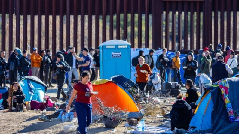 Inmigrantes ilegales que pasaron por una brecha en el muro fronterizo de EE. UU. esperan ser procesados por agentes de la Patrulla Fronteriza en Jacumba, California, el 7 de diciembre de 2023. (John Fredricks/The Epoch Times)