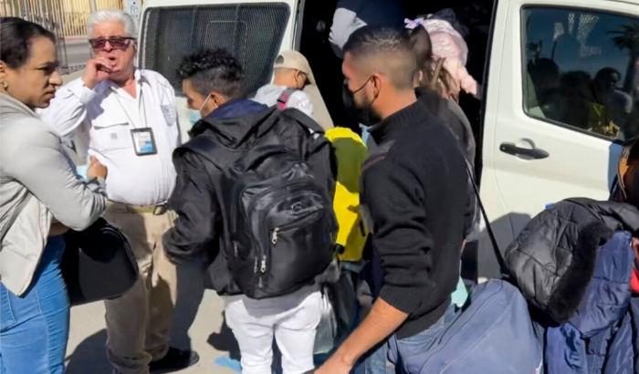 Un funcionario de inmigración mexicano espera mientras los migrantes con autoridad de libertad condicional aprobada por Estados Unidos esperan para abordar su camioneta lista para cruzar a Estados Unidos a través de un puerto de entrada. (Cortesía de Todd Bensman/Centro de Estudios de Inmigración)