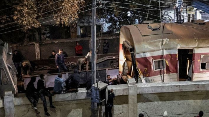 Imagen de archivo. La gente se reúne junto a una pared que acota la vía del ferrocarril mientras se despliega una grúa para levantar un tren descarrilado en el lugar de un accidente ferroviario en la ciudad de Qalyub, provincia de Qalyub, en la región del delta del Nilo al norte de la capital egipcia, el 7 de marzo de 2023. (KHALED DESOUKI/AFP a través de Getty Images)