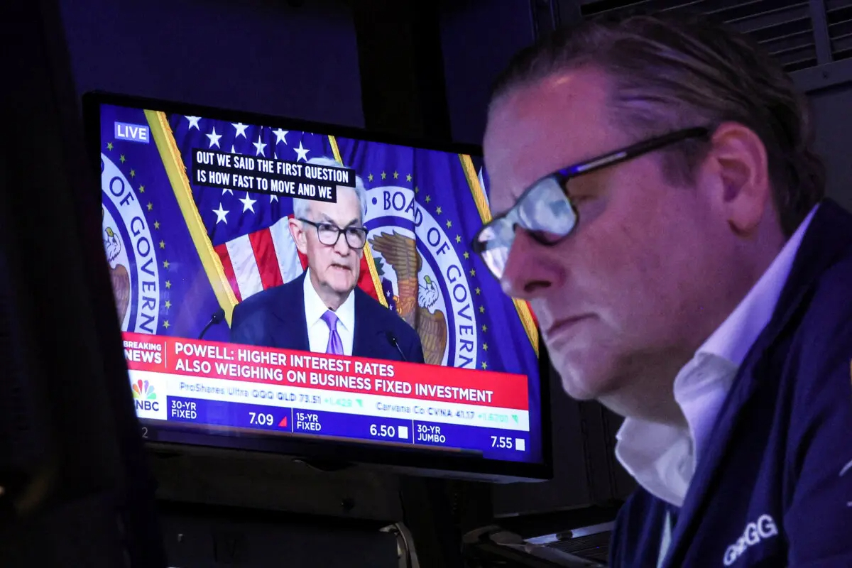 Un comerciante trabaja mientras una pantalla muestra una conferencia de prensa del presidente de la Reserva Federal, Jerome Powell, tras el anuncio de tipos de la Fed en el parqué de la Bolsa de Nueva York el 13 de diciembre de 2023. (Brendan McDermid/Reuters)