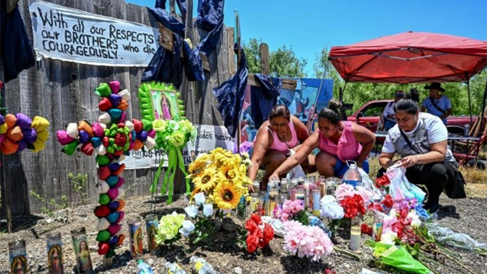 La gente coloca flores y velas en un monumento improvisado donde se descubrió un tractor-remolque con inmigrantes ilegales fallecidos en el interior, cerca de San Antonio, Texas, el 29 de junio de 2022. (Chandan Khanna/AFP vía Getty Images)