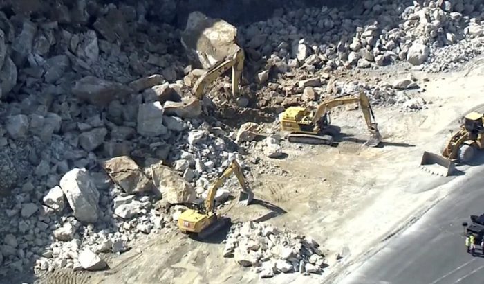 Esta imagen tomada de un video muestra una excavadora, arriba a la izquierda, enterrada bajo rocas y cantos rodados, el 22 de agosto de 2024, en una cantera en Sterling, Massachusetts, según imágenes de video aéreas de estaciones de noticias locales. (WCVB-TV vía AP)