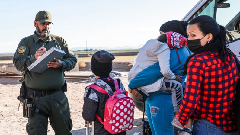 Un agente de la Patrulla Fronteriza organiza a inmigrantes ilegales que se han reunido junto a la valla fronteriza después de cruzar de México a Estados Unidos, en Yuma, Arizona, el 10 de diciembre de 2021. (Charlotte Cuthbertson/The Epoch Times)