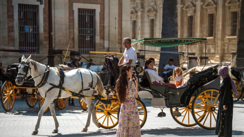 Un turista toma una foto durante un recorrido en coche de caballos en Sevilla, el 6 de julio de 2024. (Foto de CRISTINA QUICLER/AFP vía Getty Images)