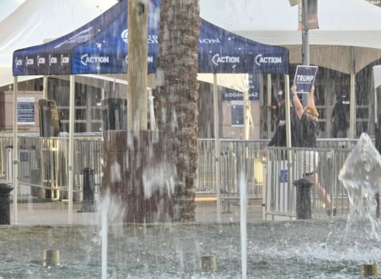 Una mujer con un cartel de Trump pasa junto a una fuente de agua en Glendale, Arizona, el 23 de agosto de 2024. (Allan Stein/The Epoch Times)