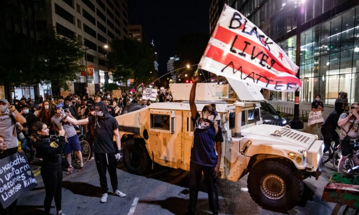 Un manifestante agita una bandera de DC con Black Lives Matter pintada con aerosol mientras los manifestantes marchan por las calles durante una manifestación por la muerte de George Floyd, que murió bajo custodia policial, en Washington el 2 de junio de 2020. Samuel Corum/Getty Images