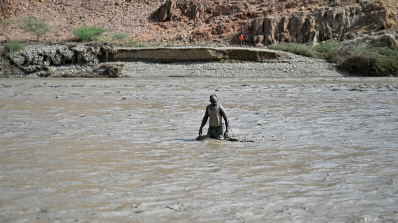 Un hombre sudanés se adentra en aguas fangosas tras el colapso de la presa Arbaat, a 40 km al norte de Puerto Sudán, luego de fuertes lluvias e inundaciones torrenciales el 25 de agosto de 2024. (AFP via Getty Images)