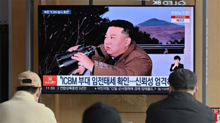 Un grupo de personas en una estación de ferrocarril de Seúl, Corea del Sur, observa un informativo de televisión que muestra una foto del líder norcoreano Kim Jong Un presenciando el disparo de prueba de un misil balístico intercontinental Hwasong-17 el 17 de marzo de 2023. (Jung Yeon-je/AFP vía Getty Images)
