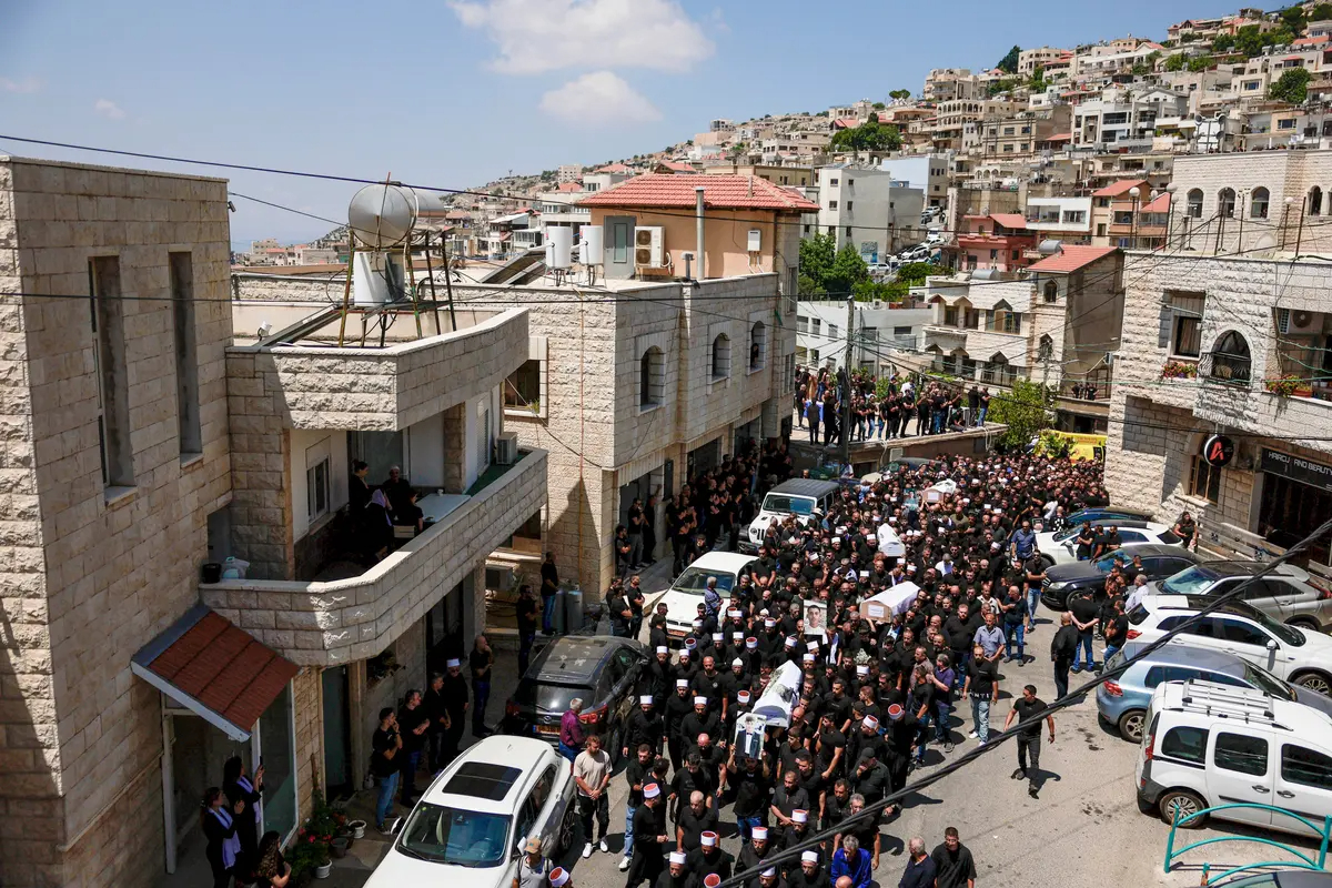 Dolientes llevan ataúdes, durante el funeral de los niños que murieron en un campo de fútbol por un cohete que Israel dice que fue disparado desde el Líbano, en Majdal Shams, un pueblo druso en los Altos del Golán, el 28 de julio de 2024. (Ammar Awad/Reuters)