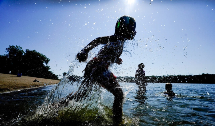 Judah Boyle, de Des Moines, Iowa, salpica agua mientras corre por la playa del parque Gray's Lake, en Des Moines, Iowa, el 26 de agosto de 2024. (Charlie Neibergall/Foto AP)