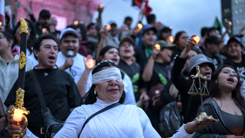 Una mujer vestida como la Dama Justicia participa en una vigilia vistiendo ropa negra y portando velas como protesta contra la reforma judicial propuesta por el gobierno en la plaza del Ángel de La Independencia en la Ciudad de México (México) el 26 de agosto de 2024. (Yuri Cortez/AFP vía Getty Images)