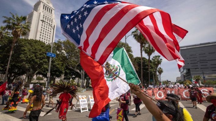 Personas portan las banderas de Estados Unidos y México frente al Ayuntamiento de Los Ángeles, en Los Ángeles, California, el 1 de mayo de 2021.  (DAVID MCNEW/AFP vía Getty Images)