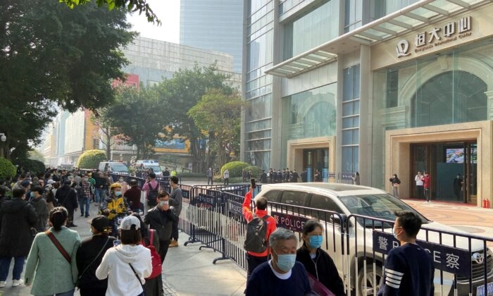 Protestantes que exigen pagos del Grupo China Evergrande se reúnen mientras oficiales de policía permanecen en guardia frente al Centro Internacional de Evergrande en Guangzhou, provincia de Guangdong, China, el 4 de enero de 2022. (David Kirton/Reuters)