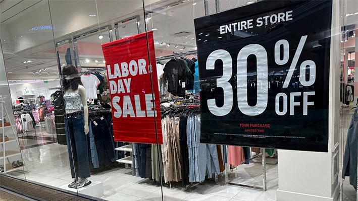 Carteles anunciando las rebajas del Día del Trabajo cuelgan del escaparate de una tienda de ropa en un centro comercial de Denver el 21 de agosto de 2024. (David Zalubowski /AP Photo)
