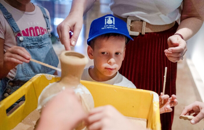 Ariel Geller de 4 años, ayuda a pegar un jarrón de arcilla rota durante una visita especial con su familia después de que rompiera accidentalmente otro jarrón en el Museo Reuben y Edith Hecht en Haifa, Israel, el 30 de agosto de 2024. (Maya Alleruzzo/Foto AP)
