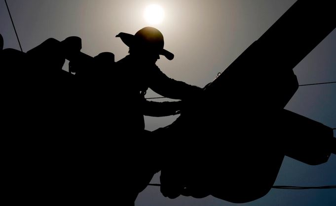 Un electricista trabaja en las líneas eléctricas bajo el Sol de la mañana, en Phoenix el 12 de julio de 2024. (Matt York/Foto AP)