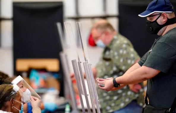 Un votante (de) muestra su identificación a un empleado electoral del condado de Harris (iz) antes de votar en Houston, Texas, el 14 de julio de 2020. (David J. Phillip/Foto AP)