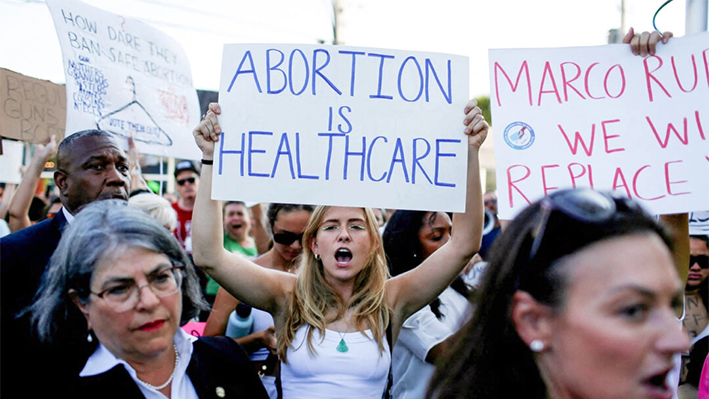 Una manifestante sostiene un cartel mientras se manifiesta en Miami tras la sentencia de la Corte Suprema de EE. UU. en el caso del aborto Dobbs vs Jackson Women's Health Organization, que anuló la histórica decisión sobre el aborto Roe vs Wade, el 24 de junio de 2022. (Marco Bello/Reuters)
