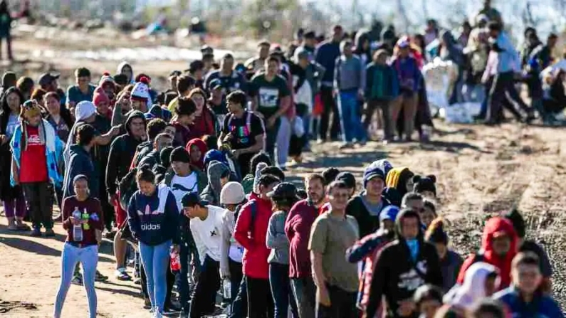 Más de 1000 inmigrantes ilegales esperan en fila para ser procesados por agentes de la Patrulla Fronteriza de EE.UU. después de cruzar el Río Grande desde México en Eagle Pass, Texas, el 18 de diciembre de 2023. (John Moore/Getty Images)