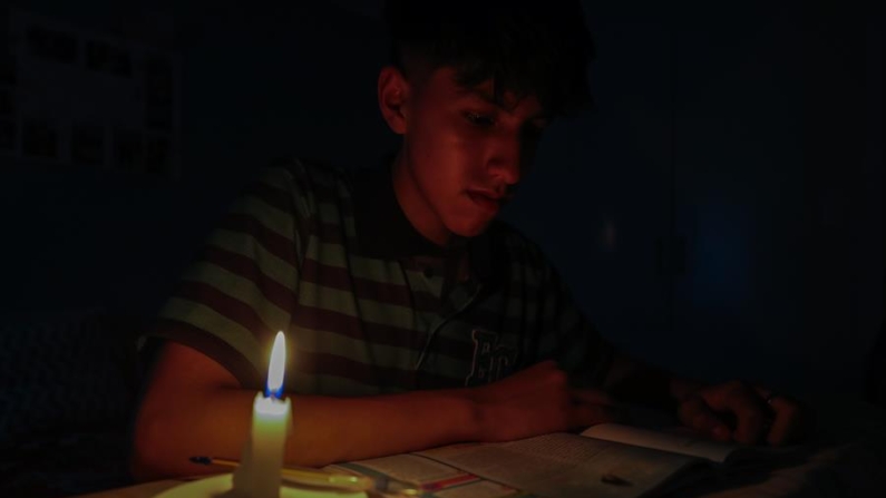 Fotografía de archivo en donde se ve a un estudiante que lee un texto a la luz de una vela en Quito (Ecuador). EFE/José Jácome
