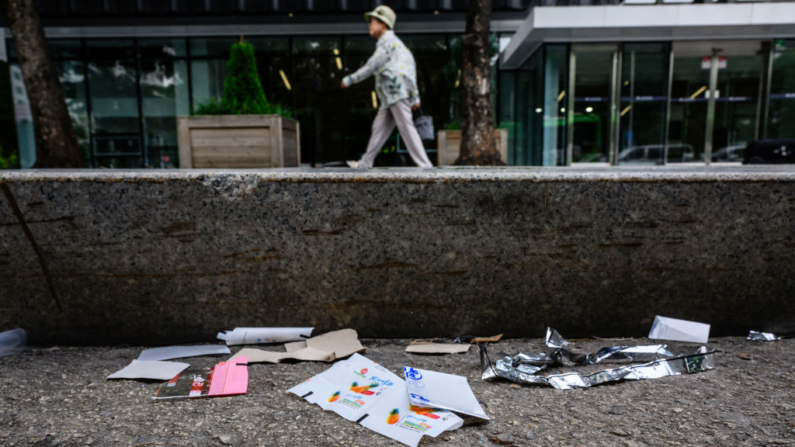 Un peatón camina por una acera junto a trozos de envases de alimentos norcoreanos, envoltorios de dulces y papel que se sospecha provienen de globos de basura enviados desde Corea del Norte, en Seúl el 24 de julio de 2024. (Anthony Wallace/AFP vía Getty Images)