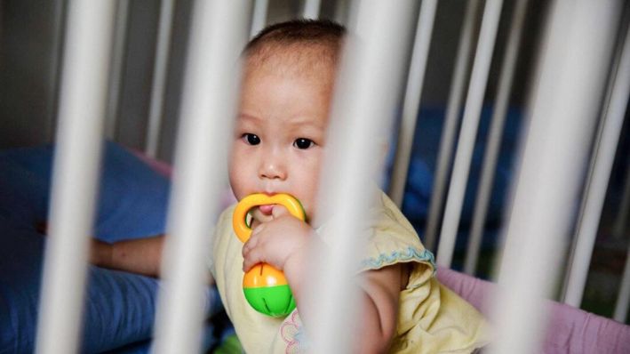 Una niña china huérfana se sienta en una cuna en un centro de acogida en Beijing el 2 de abril de 2014. (Kevin Frayer/Getty Images)