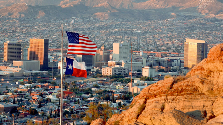 Una bandera estadounidense y texana ondean frente al horizonte de El Paso y Ciudad Juárez en El Paso, Texas, el 23 de septiembre de 2022. (Joe Raedle/Getty Images)
