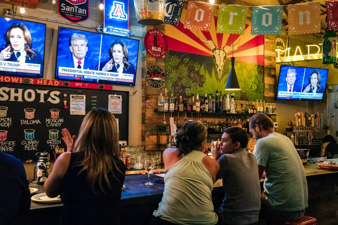 Personas sentadas detrás de una barra mientras asisten a una fiesta para ver el debate presidencial entre la vicepresidenta Kamala Harris y el expresidente Donald Trump en American Eat Co. en Tucson, Arizona, el 10 de septiembre de 2024. (Rebecca Noble/AFP vía Getty Images)