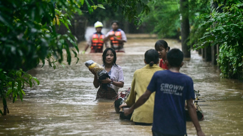 Los residentes afectados por las inundaciones cargan sus pertenencias a través de las aguas de Taungoo, en la región de Bago en Myanmar, el 12 de septiembre de 2024, tras el tifón Yagi. (Sai Aung Main/AFP vía Getty Images)