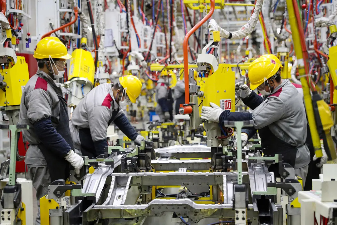 Empleados trabajando en una cadena de montaje de automóviles en una fábrica de Beijing Automotive en Qingdao, en la provincia oriental china de Shandong, el 14 de enero de 2023. (STR/AFP vía Getty Images)