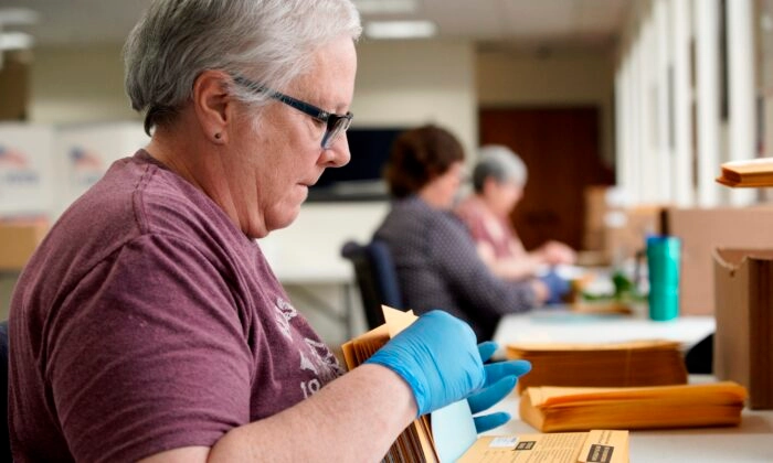 Trabajadores electorales colocan papeletas e instrucciones en sobres de correo en las oficinas del Comité Electoral del Condado de Lancaster en Lincoln, Nebraska, el 14 de abril de 2020. (Nati Harnik/Foto AP)