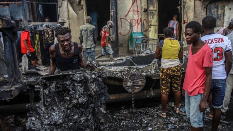 Hombres recogen piezas de aluminio en el lugar donde explotó un camión cisterna en Cap-Haitien, Haití, 14 de diciembre de 2021. (Richard Pierrin/AFP vía Getty Images)