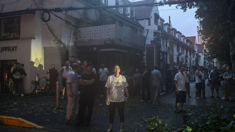 Varias personas observan cómo unos trabajadores reparan los servicios eléctricos tras el paso del tifón Bebinca en Shanghai, China, el 16 de septiembre de 2024. (Hector Retama/AFP vía Getty Images)